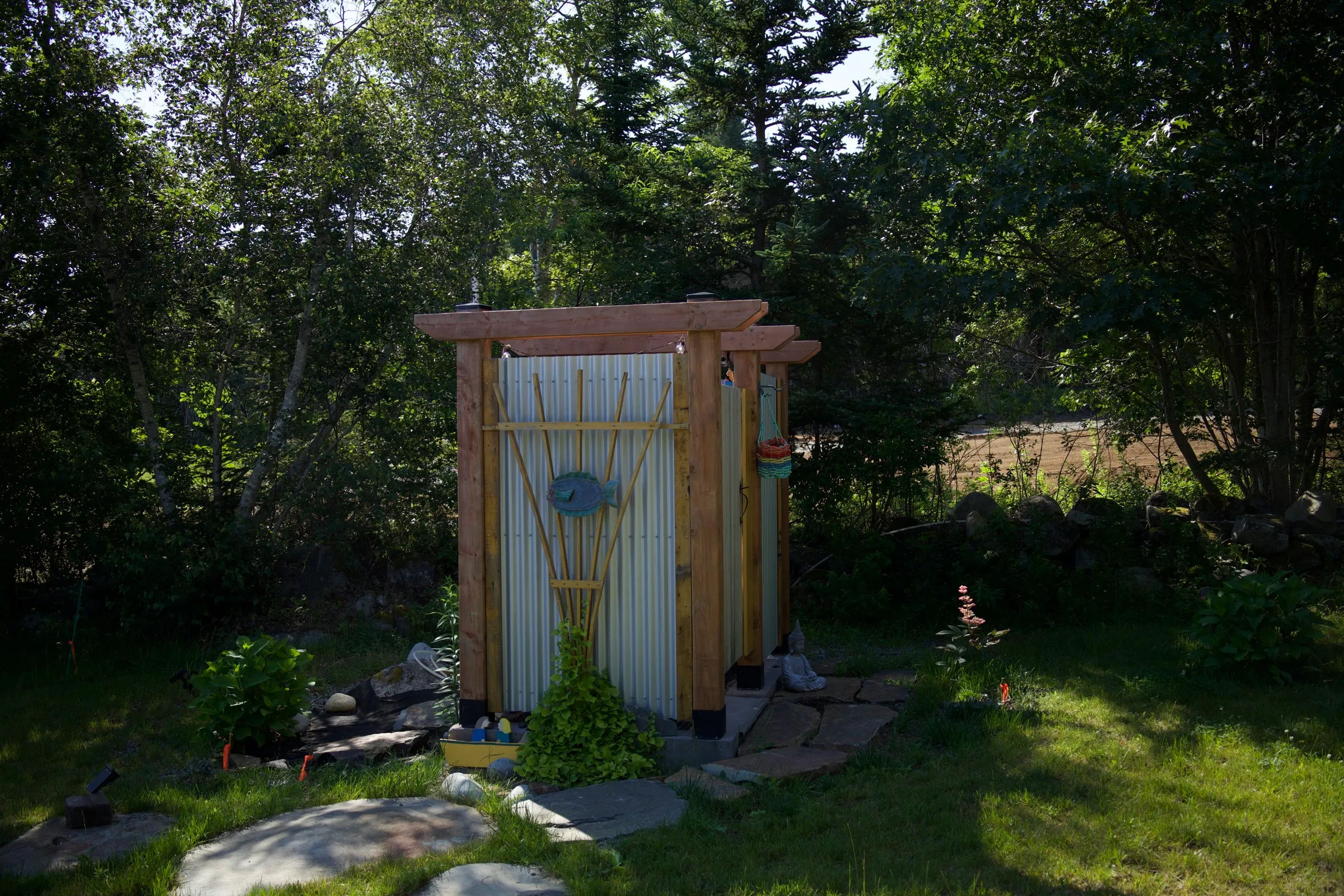 Cedar outdoor shower tucked into the greenery, with a bamboo sunburst detail