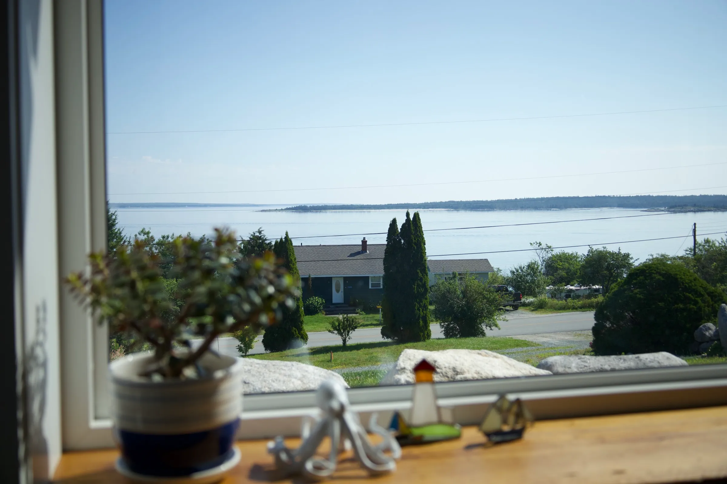 The bay framed through a cottage window, with coastal trinkets on the sill